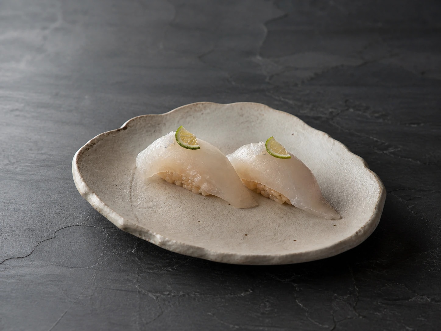 Dois nigiri de peixe branco sobre arroz akazu, com sal marinho e sudachi.