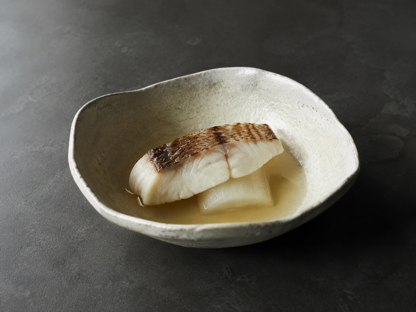 Peixe grelhado ao binchōtan, acompanhado de nabo e caldo de kombu.